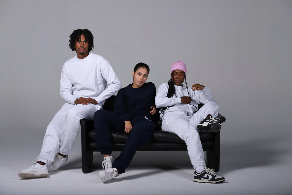 Three people sitting on a black couch against a gray background