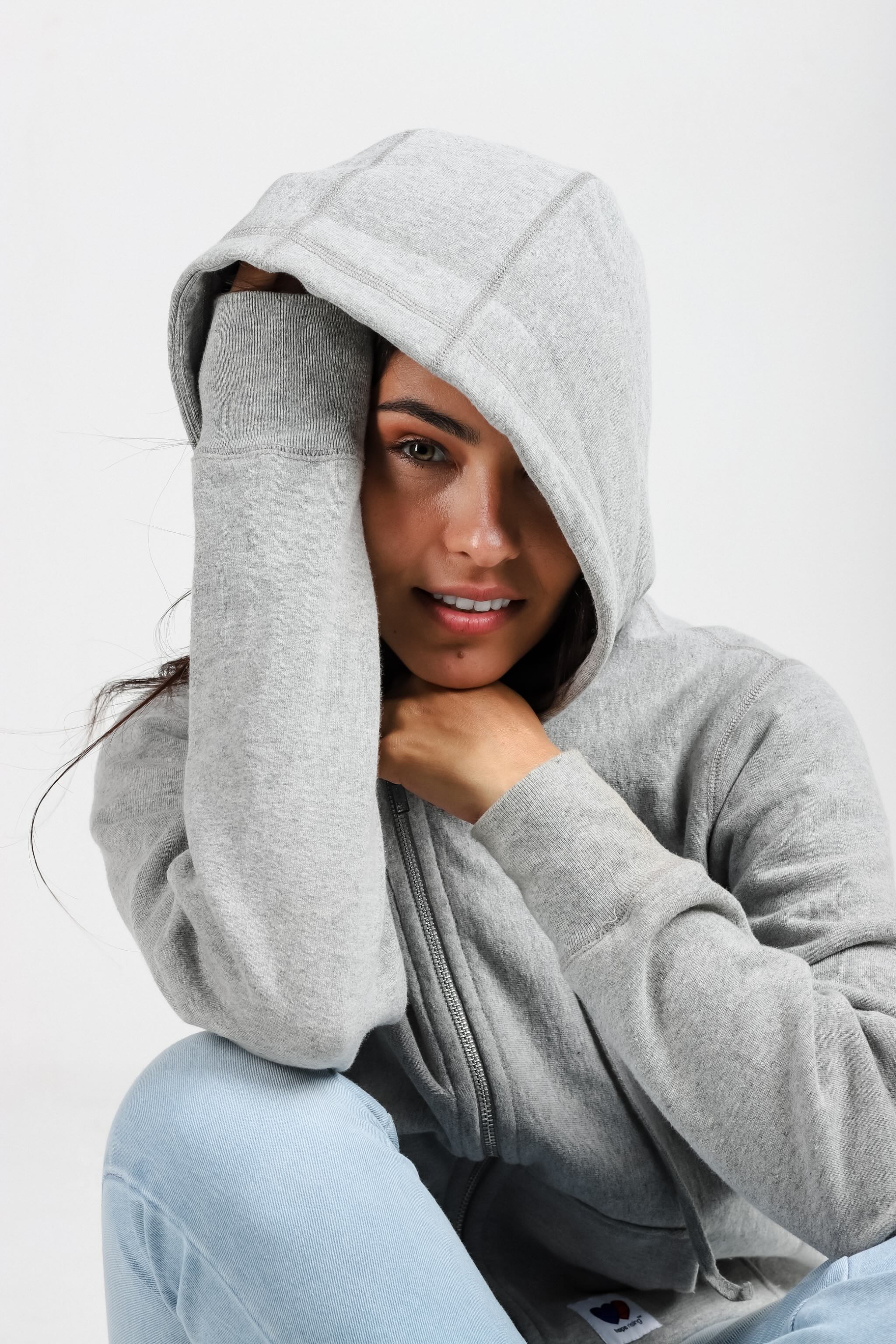 Person wearing a gray hoodie on a plain background