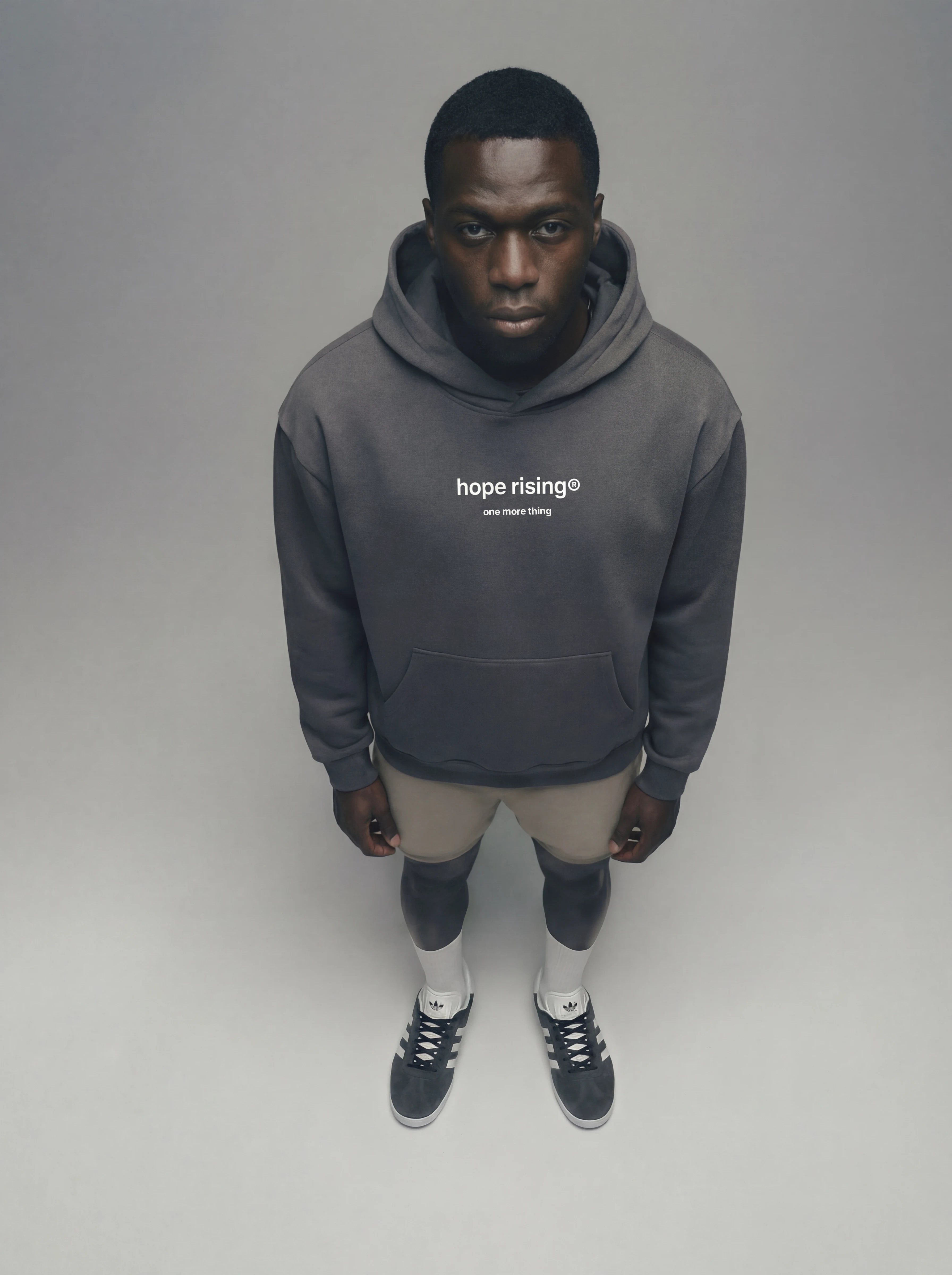Person wearing a gray hoodie with 'hope rising' text on a plain background