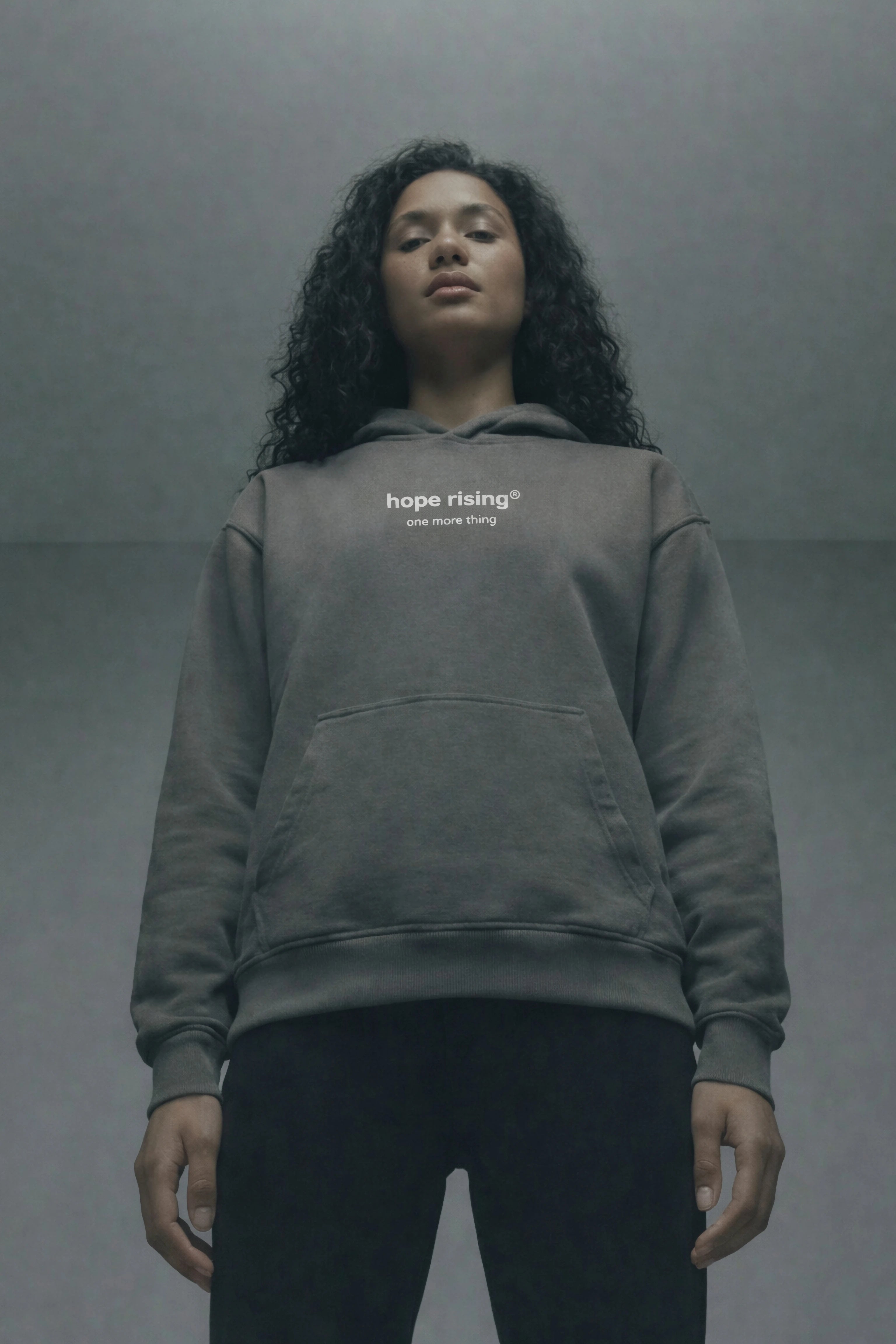 Person wearing a gray hoodie with 'hope rising' text on a gray background